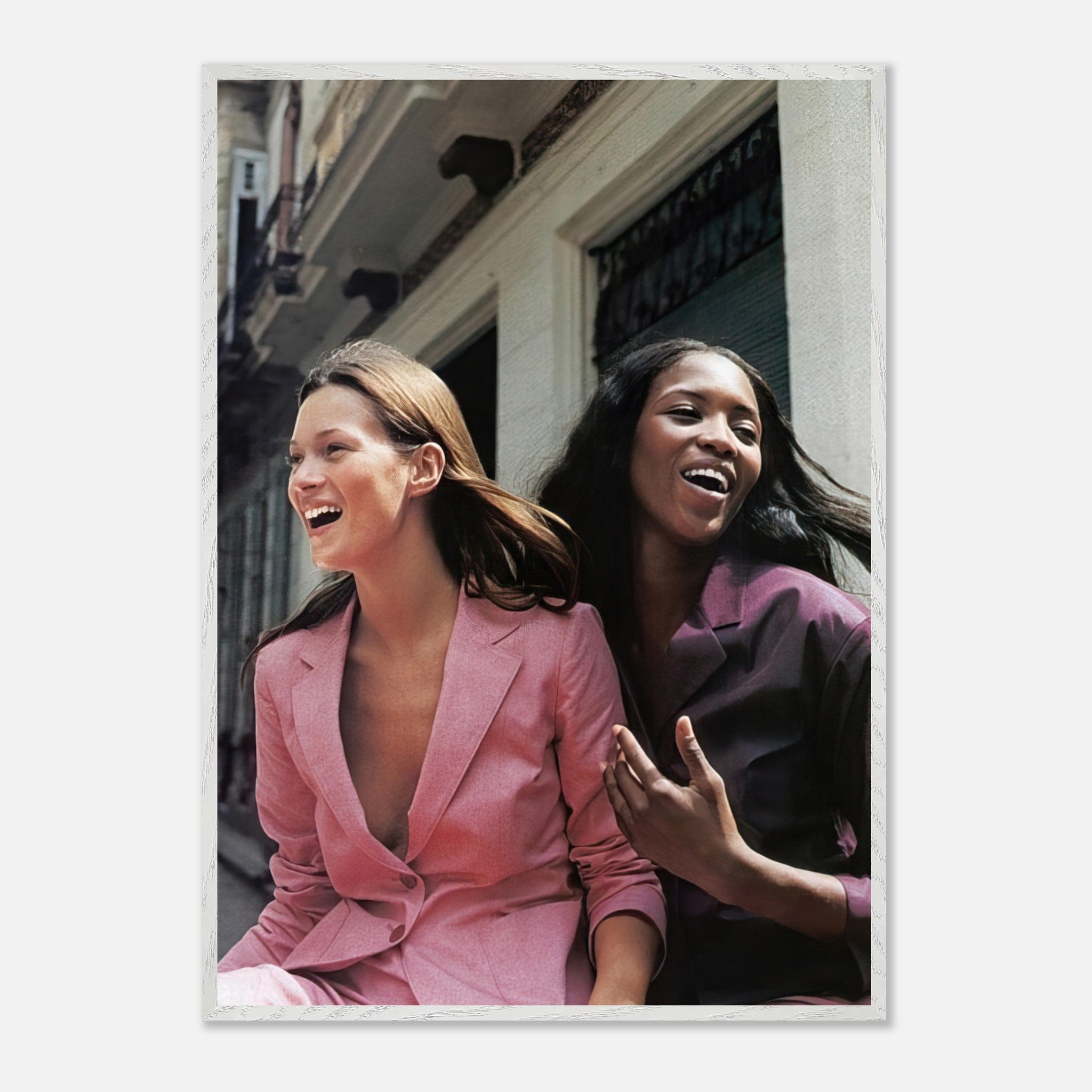 Naomi Campbell and Kate Moss laughing in stylish blazers, capturing the essence of high fashion and friendship.