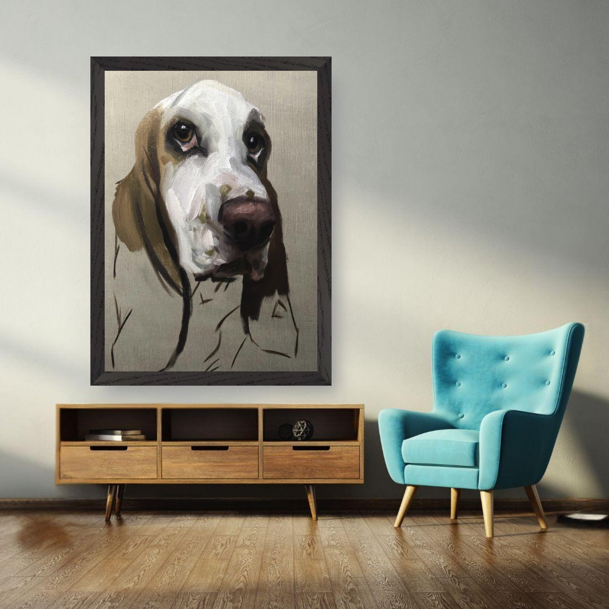 Basset Hound dog painting in vintage frame displayed on a wall beside a teal chair and wooden furniture.