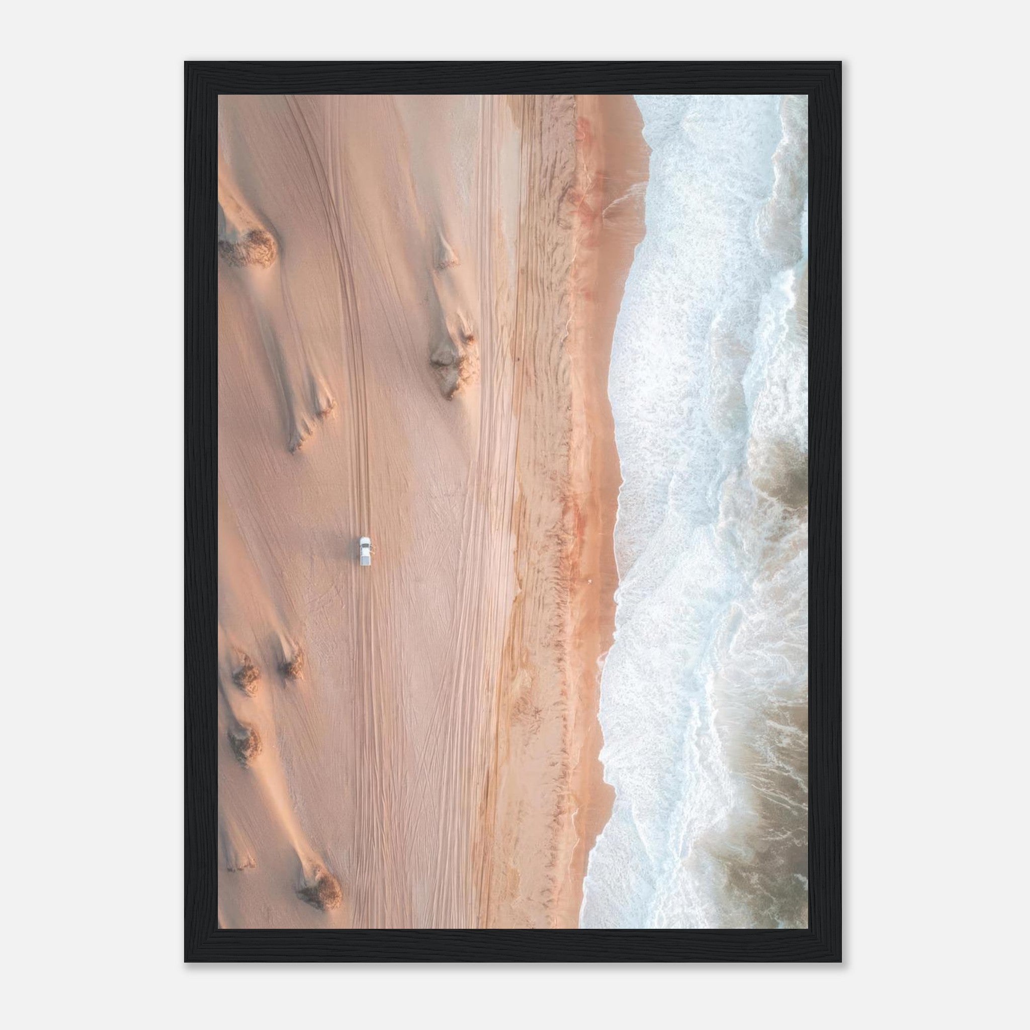 Aerial drone photography print of desert sand and ocean waves, featuring a vehicle on the beach, framed art.