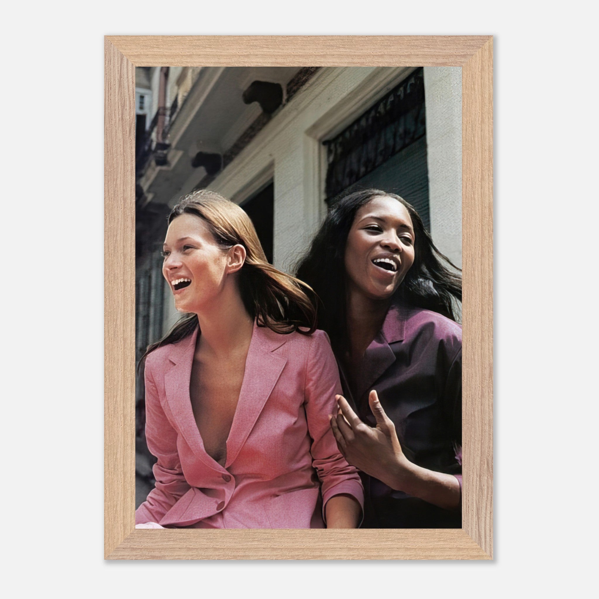 Naomi Campbell and Kate Moss laughing in vintage framed print, capturing iconic fashion history.
