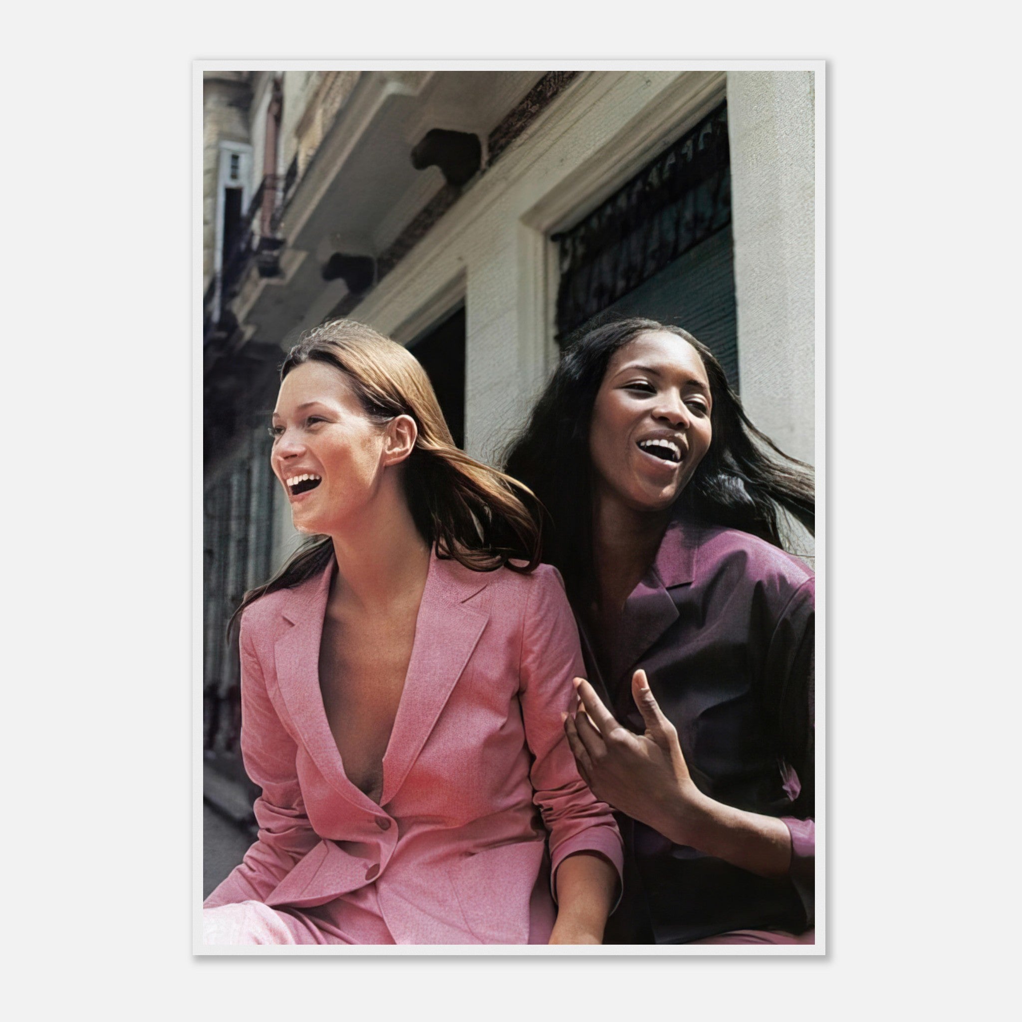 Naomi Campbell and Kate Moss laughing together in stylish suits, capturing a joyful fashion moment in a framed print.