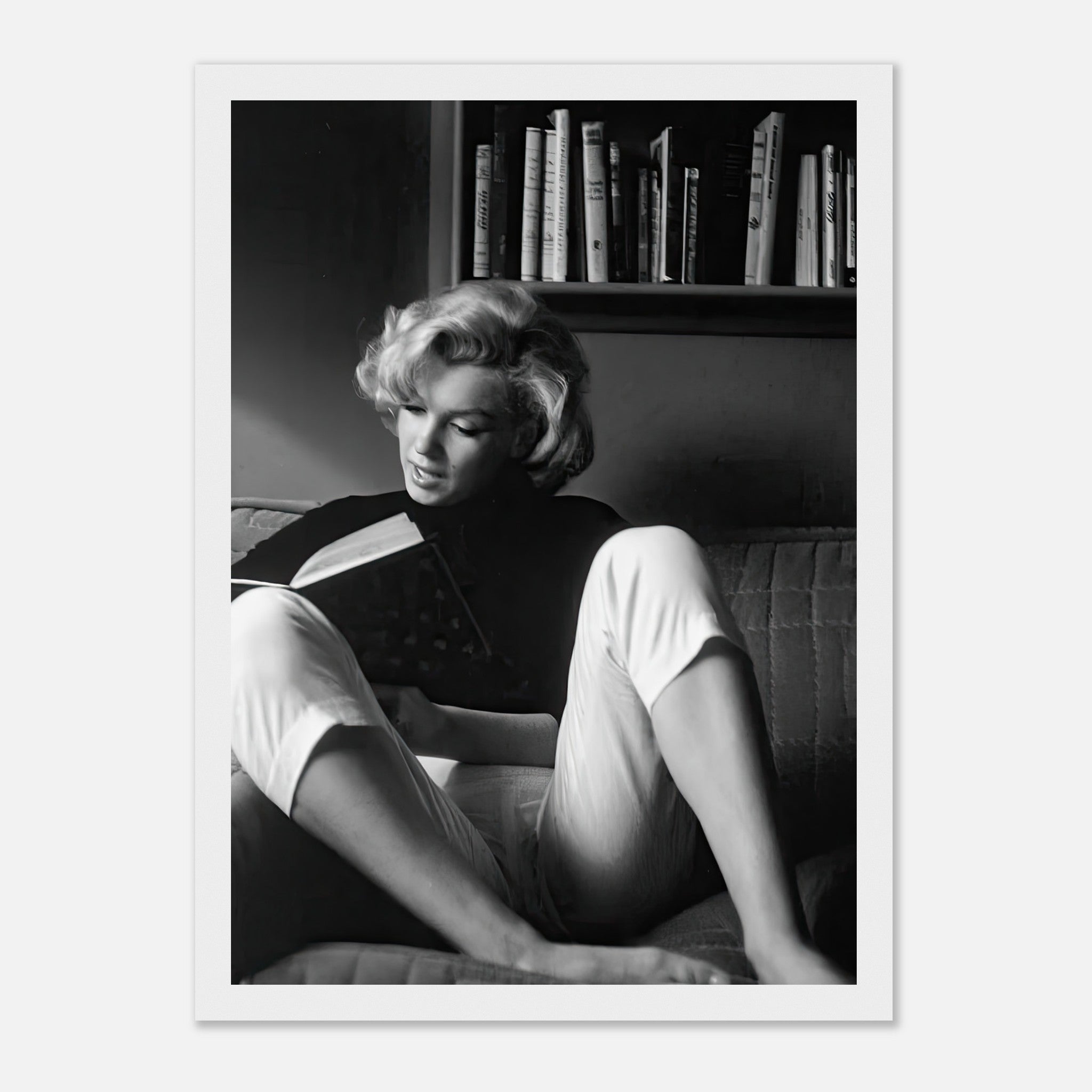 Marilyn Monroe reading a book at home, captured in a timeless black-and-white framed print.