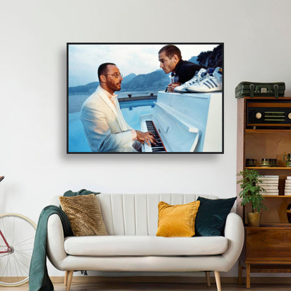 Jean Reno playing piano in serene setting with mountains; framed print adding cinematic charm to living space.