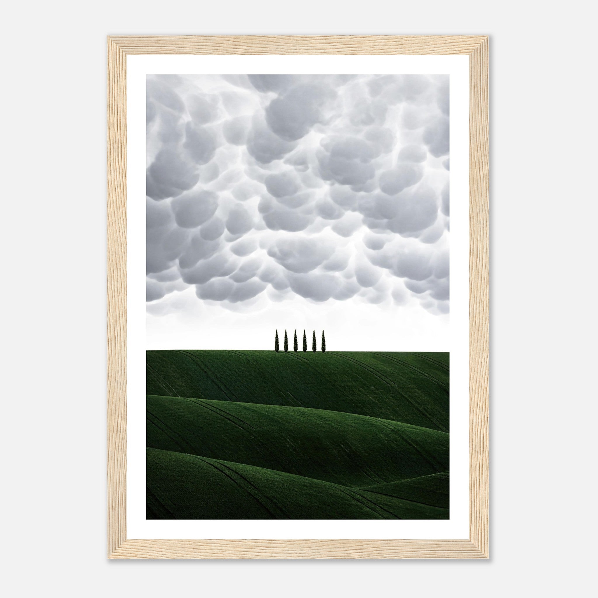 Framed print of Tuscany, Italy featuring green hills and dramatic clouds with elegant cypress trees.