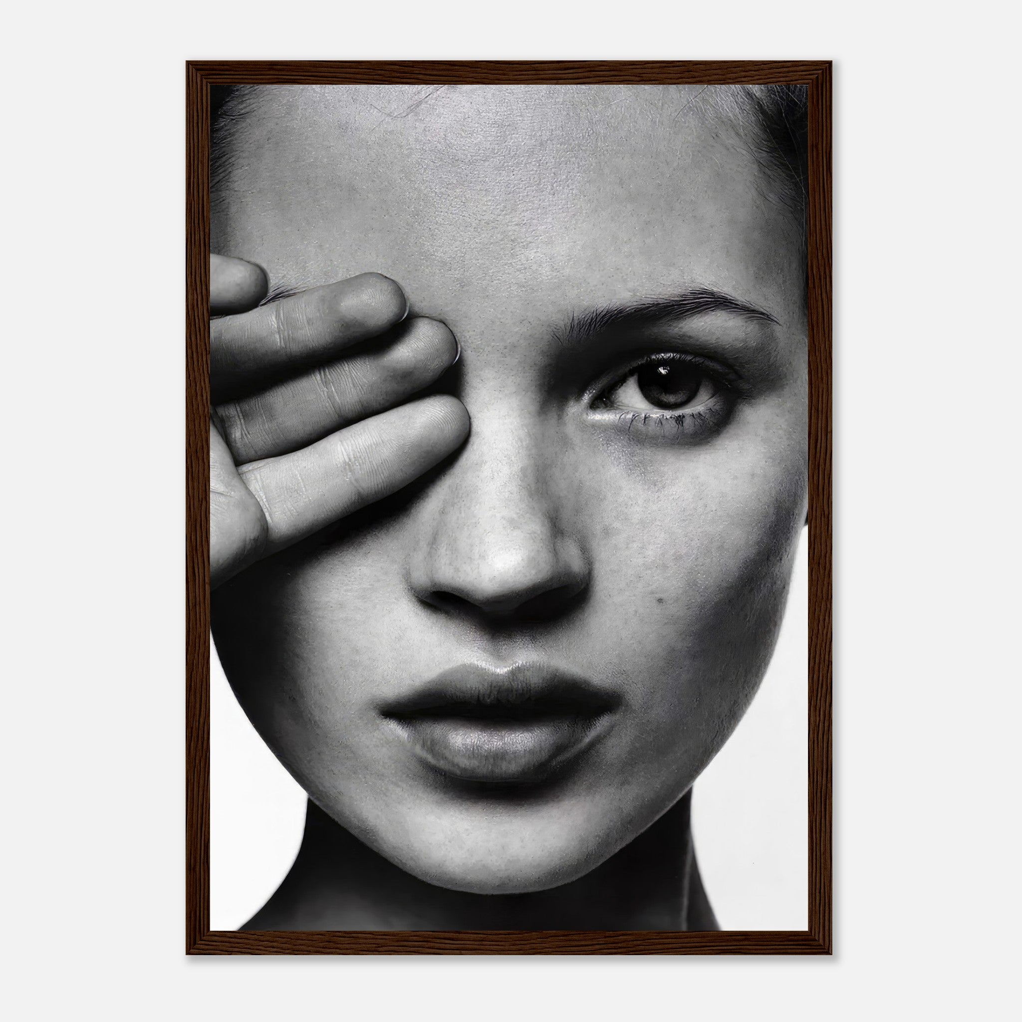 Black and white portrait of a model with a hand over her eye, framed artwork by Kate Moss, adding elegance to any décor.