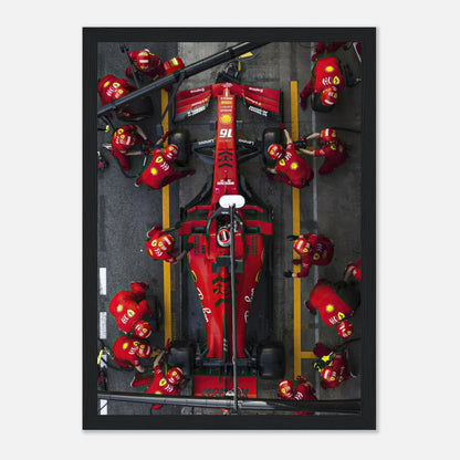 Framed print showcasing a high-speed Formula 1 Ferrari pitstop with a dynamic pit crew in vivid action.