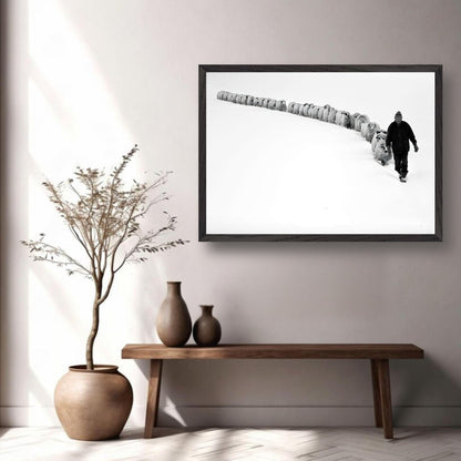 Black-and-white framed art depicting a shepherd guiding sheep through a snowy landscape in a modern interior.