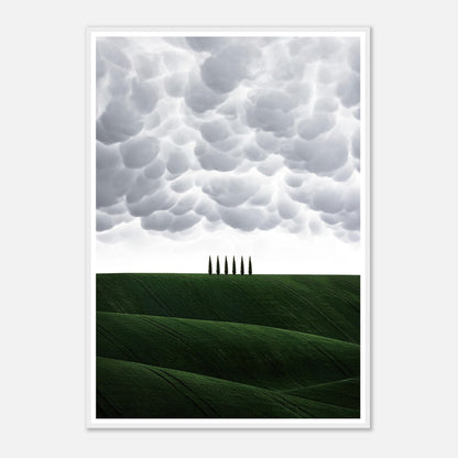 Framed print of Tuscany featuring green hills and cypress trees under dramatic cloud formations.