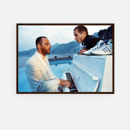 Jean Reno playing piano with a companion, framed print inspired by "The Big Blue," featuring serene ocean backdrop.