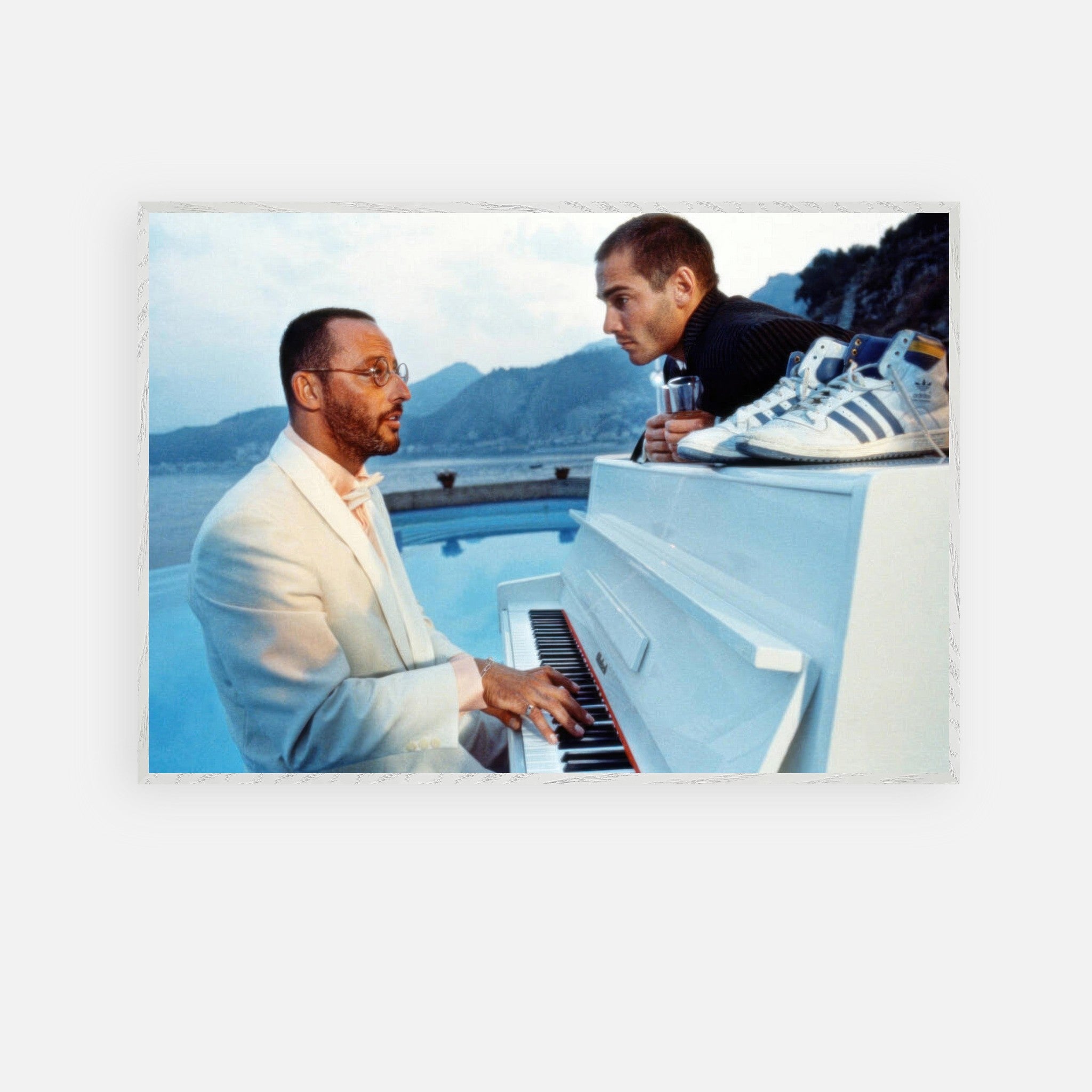 Jean Reno piano performance by a poolside with a coastal backdrop, capturing cinematic elegance and nostalgia from *The Big Blue*.