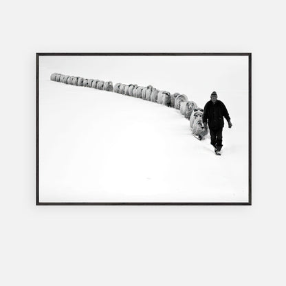Black-and-white fine art print of a shepherd walking with a flock through a snowy landscape.