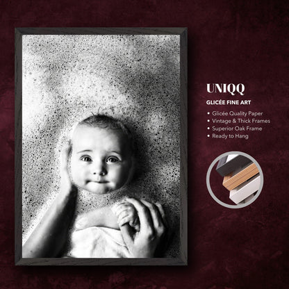 Black-and-white fine art print of a baby in a bath surrounded by bubbles, framed in vintage oak.