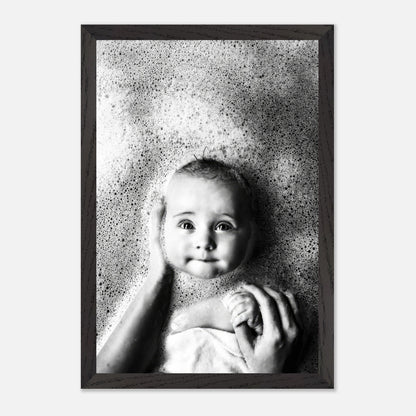 Black-and-white fine art photography of a smiling baby in a bubble bath, capturing innocence and joy.