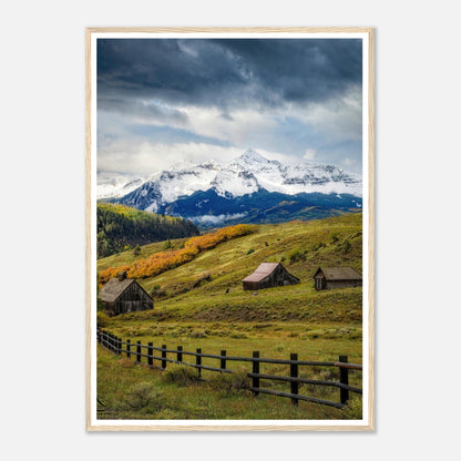 Framed print of Telluride, Colorado showcasing snow-capped peaks and rustic barns amidst vibrant meadows.