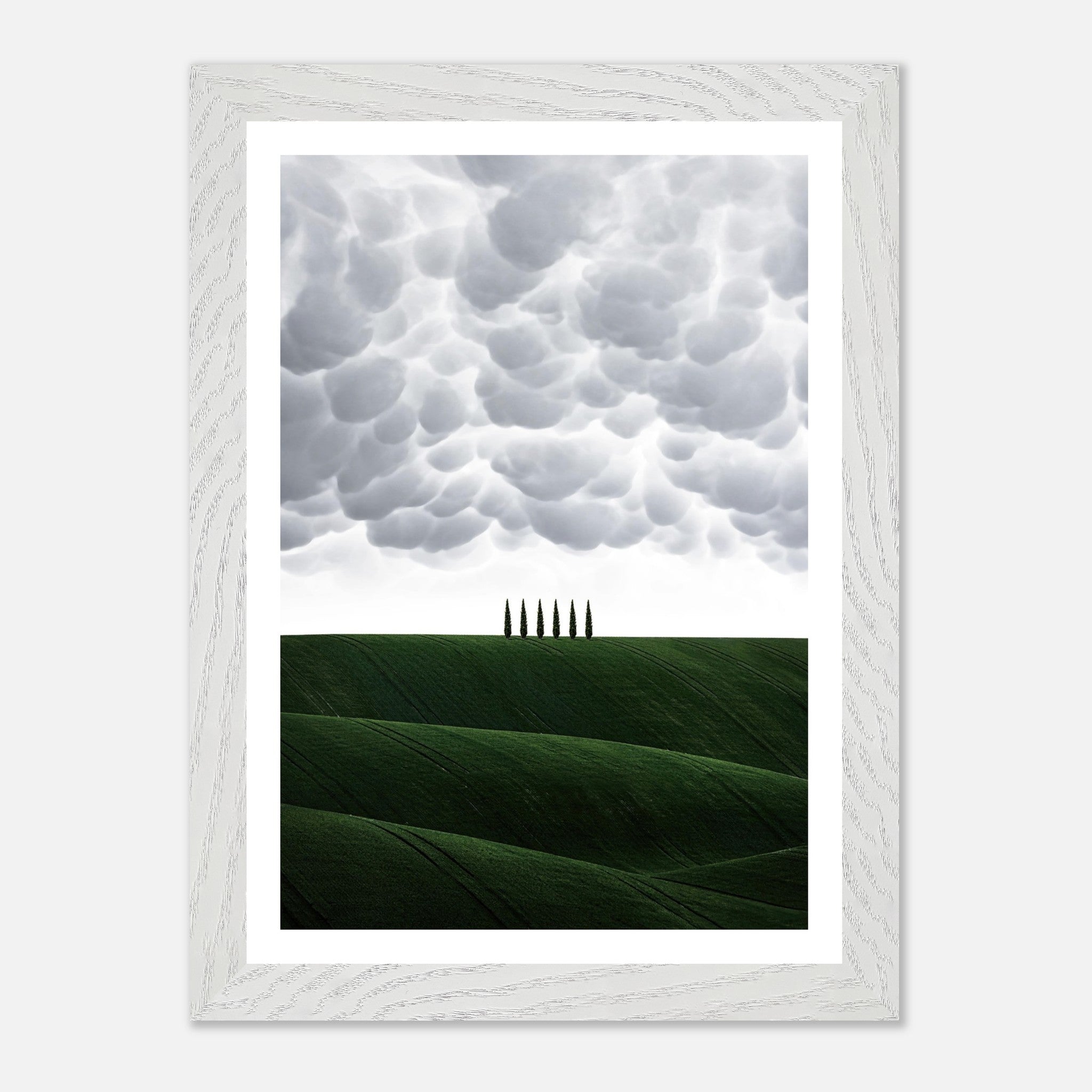 Vintage framed art of Tuscany with rolling green hills and cypress trees beneath a dramatic sky.