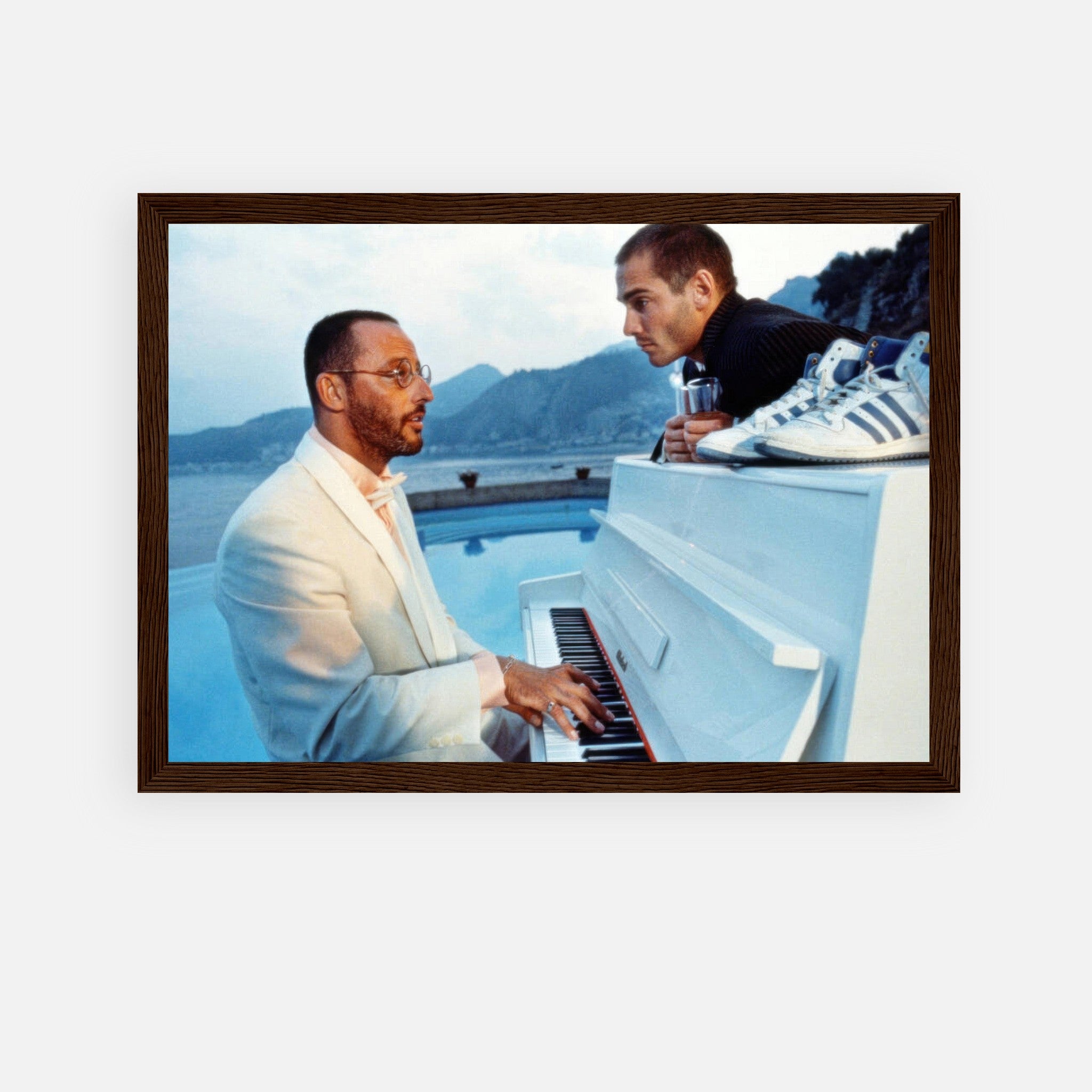 Jean Reno playing piano with a companion against a serene ocean backdrop in a framed print from "The Big Blue."