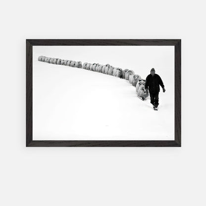 Black-and-white fine art print of a shepherd walking with his flock through a snowy landscape, embodying resilience.
