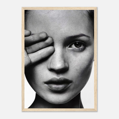 Framed black and white portrait of a woman covering one eye, showcasing modern elegance in décor.