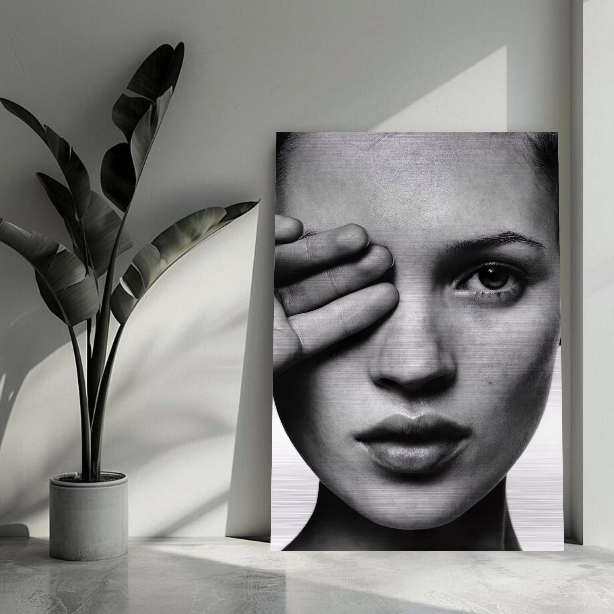 Black and white portrait of Kate Moss on brushed metal, showcasing timeless beauty in a modern space with greenery.