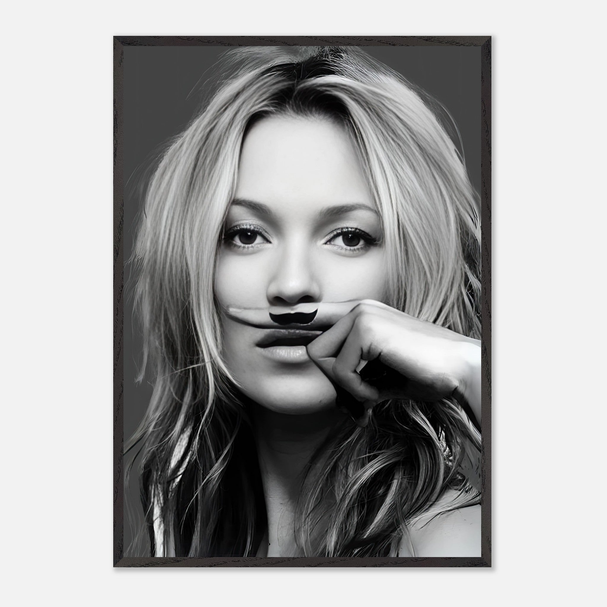 Black-and-white vintage framed print of Kate Moss playfully posing with a mustache, adding humor to wall decor.