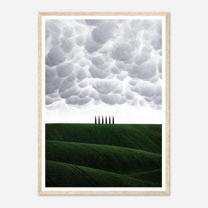 Framed print of Tuscany's rolling green hills under dramatic clouds, featuring elegant cypress trees.