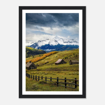 Telluride, Colorado framed print showcasing snowy peaks, rustic barns, and vibrant meadows under a dramatic sky.