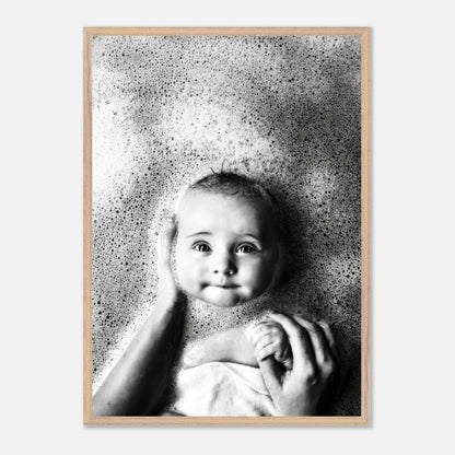 Black-and-white fine art print of a smiling baby in a bubble bath, capturing innocence and joy.