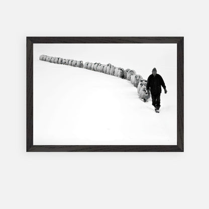 Black-and-white photograph of a shepherd guiding sheep through a snow-covered landscape, framed art.