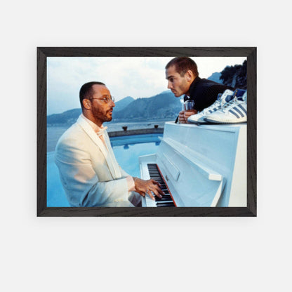 Jean Reno playing piano in framed print from "The Big Blue," featuring a scenic seaside backdrop.