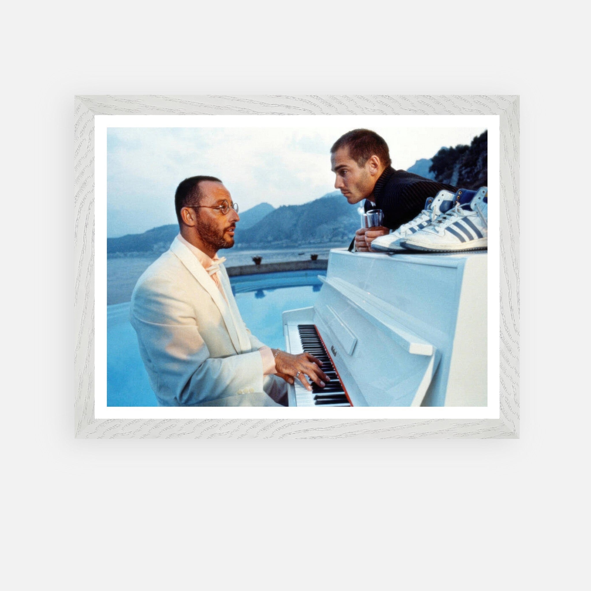 Framed print of Jean Reno playing piano with a serene seaside backdrop from iconic film "The Big Blue."