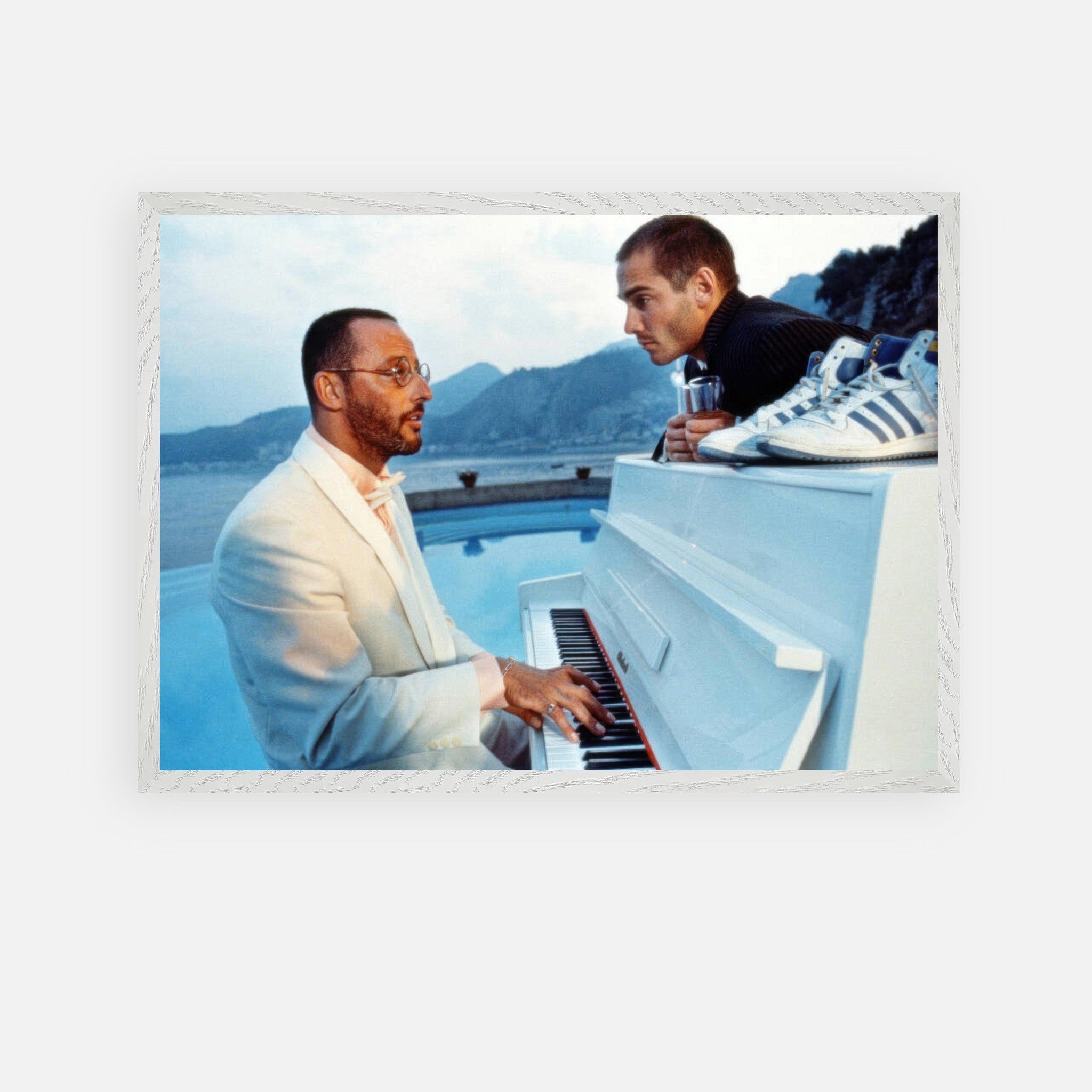 Jean Reno playing piano on the set of "The Big Blue" with serene seaside backdrop, vintage framed print.