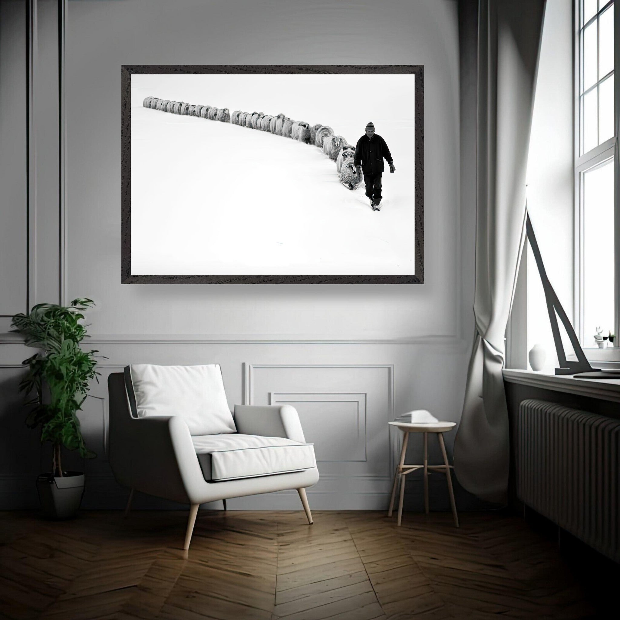 Black-and-white fine art print of a shepherd leading his flock through snowy terrain in a modern interior.
