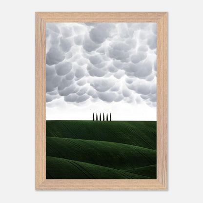 Vintage framed art of Tuscany featuring green hills and cypress trees under a dramatic sky. Perfect for home decor.