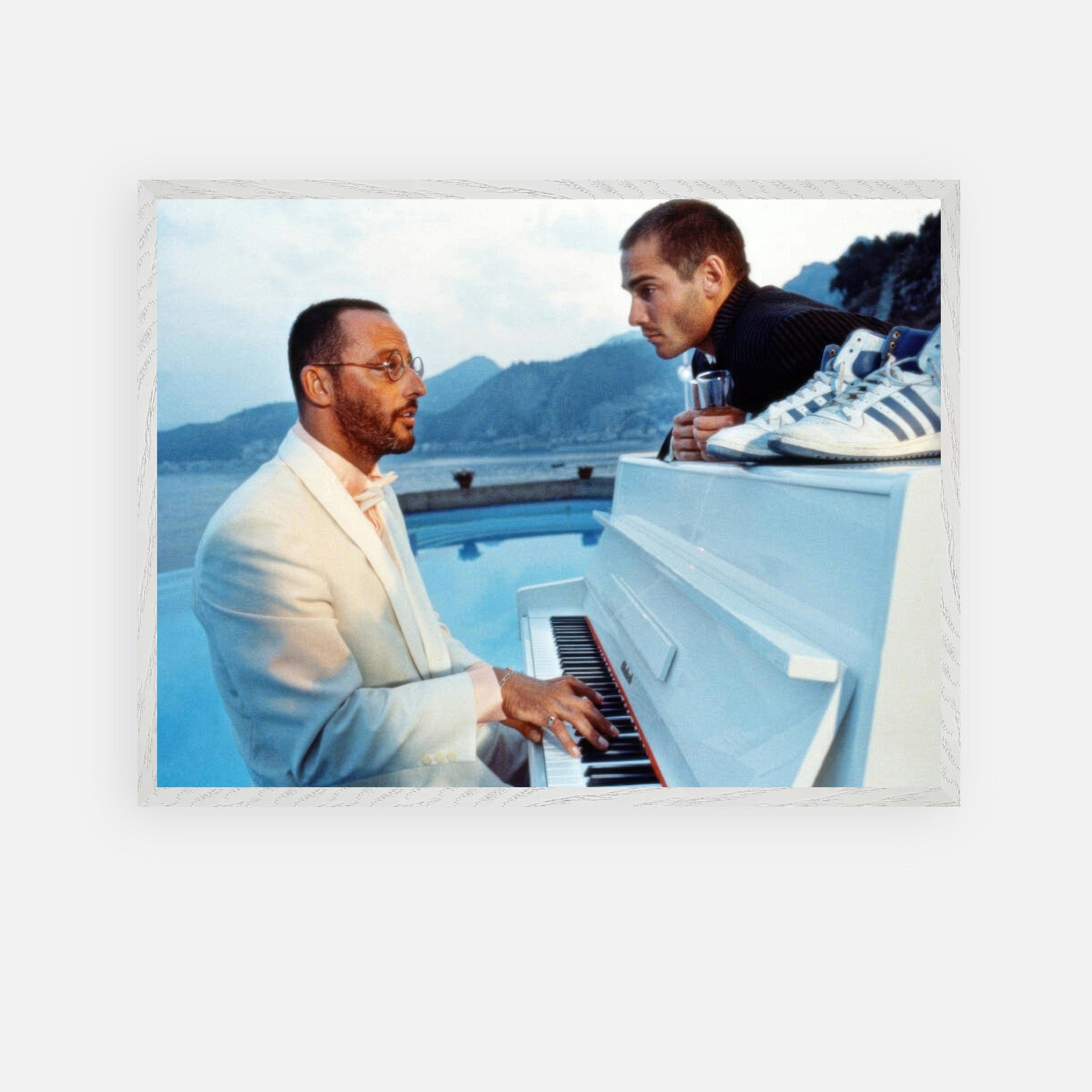 Jean Reno playing piano outdoors with a serene seaside backdrop in a vintage framed print.