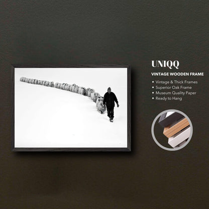 Black-and-white vintage framed art of a shepherd leading sheep through snow-covered terrain.