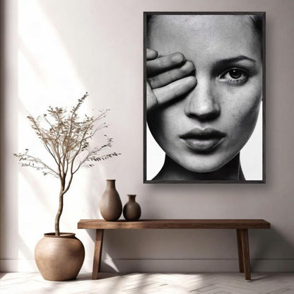 Kate Moss black and white photography framed print on wall, modern decor with potted plant and vase on wooden table.