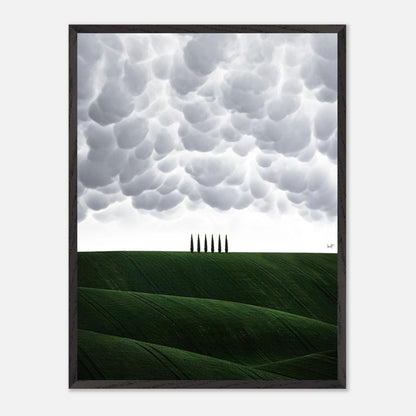 Vintage framed art depicting Tuscany's green hills and cypress trees under dramatic clouds.