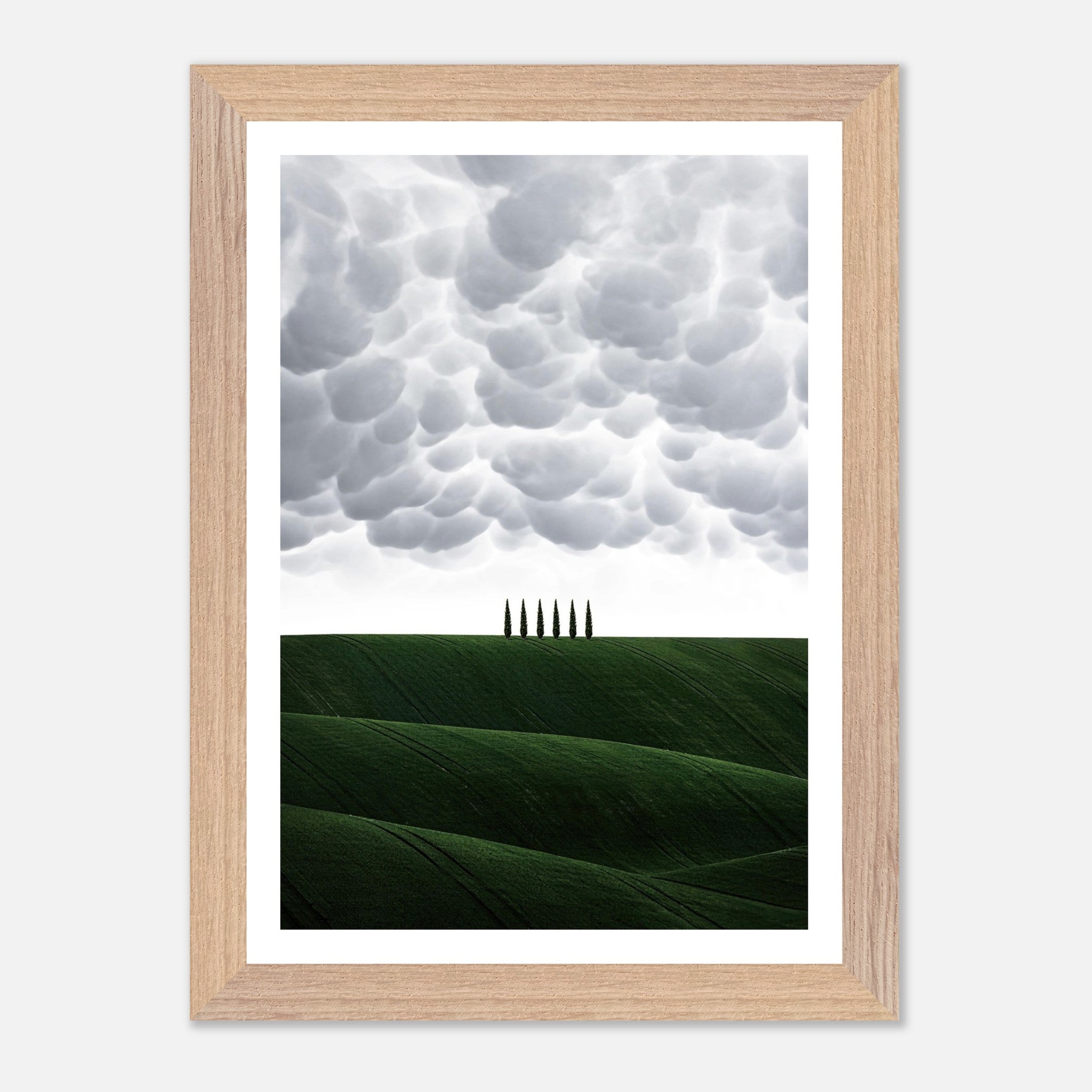 Vintage framed art depicting Tuscany's rolling green hills and cypress trees beneath a dramatic sky.