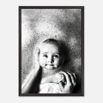 Vintage black and white photograph of a smiling baby in a bubble bath, framed in a classic black frame.