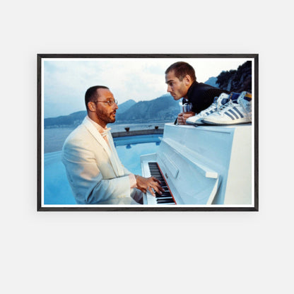 Vintage framed print of Jean Reno playing piano on the set of "The Big Blue" with a serene seaside backdrop.