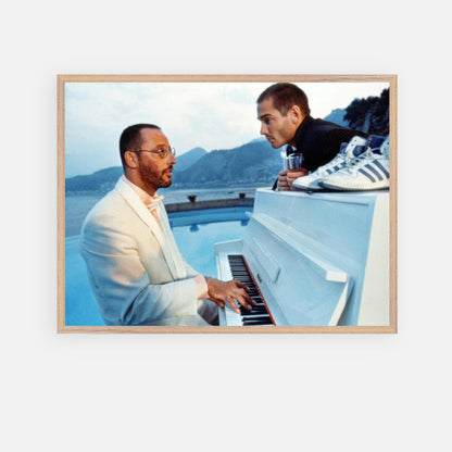 Jean Reno playing piano on set of "The Big Blue," framed print capturing a cinematic moment by the seaside.