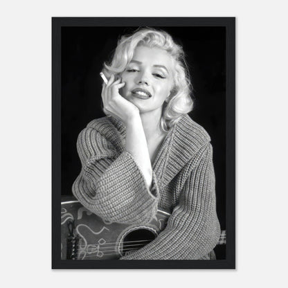 Marilyn Monroe elegantly poses with a cigarette, wearing a knit sweater in a classic black-and-white framed poster.