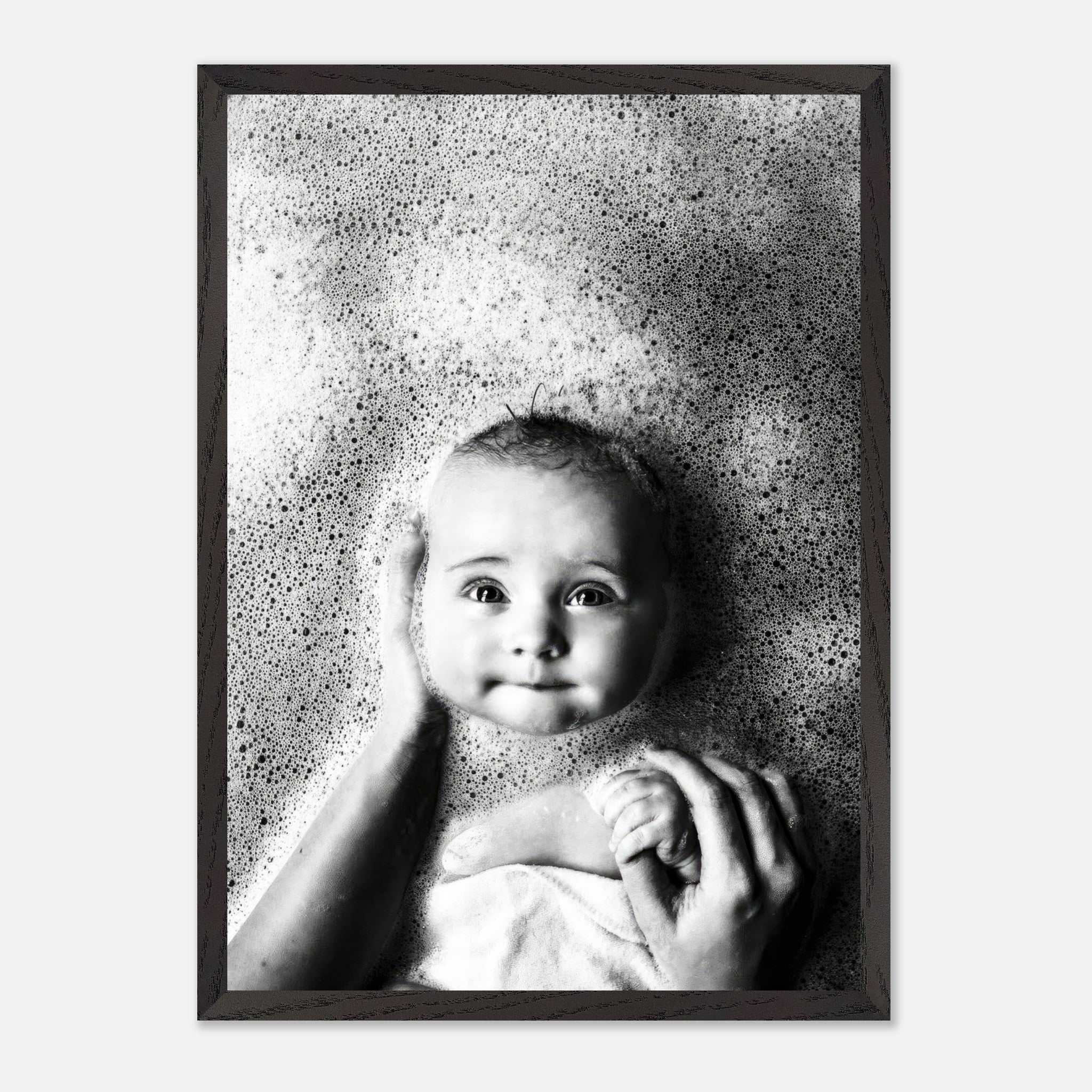 Black-and-white fine art print of a smiling baby in a bubble bath, capturing joy and innocence.