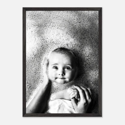 Black-and-white fine art print of a smiling baby in a bubble bath, capturing joy and innocence.