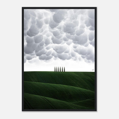 Framed print of Tuscany's rolling green hills with cypress trees under dramatic cloud formations.