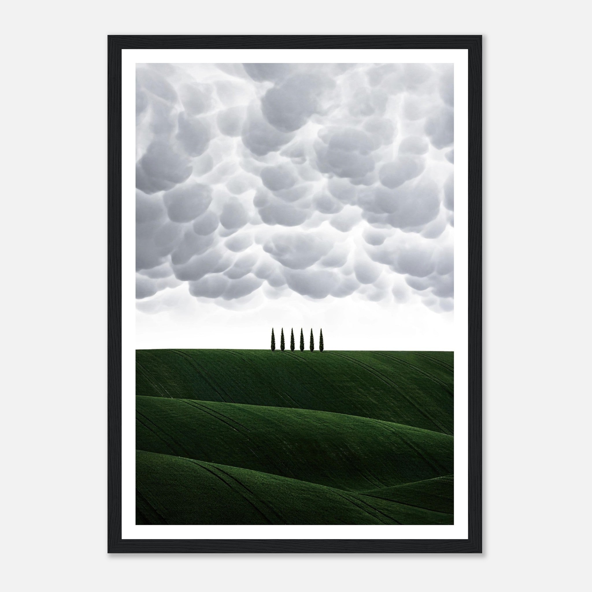 Framed print of Tuscany's rolling green hills and cypress trees under dramatic clouds, perfect for elegant home decor.