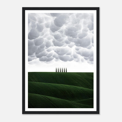 Framed print of Tuscany's rolling green hills and cypress trees under dramatic clouds, perfect for elegant home decor.