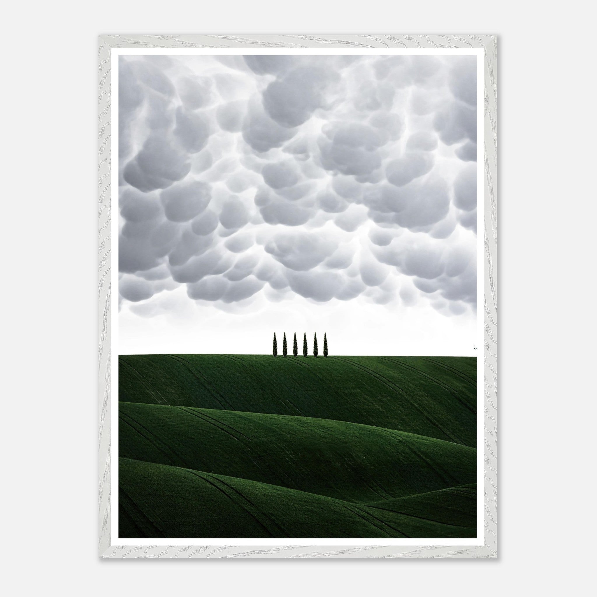 Vintage framed art of Tuscany featuring rolling green hills and cypress trees under a dramatic cloudy sky.