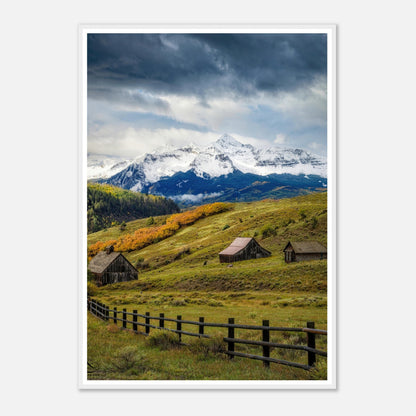 Stunning framed print of Telluride, Colorado featuring snow-capped peaks and rustic barns in a vibrant meadow.