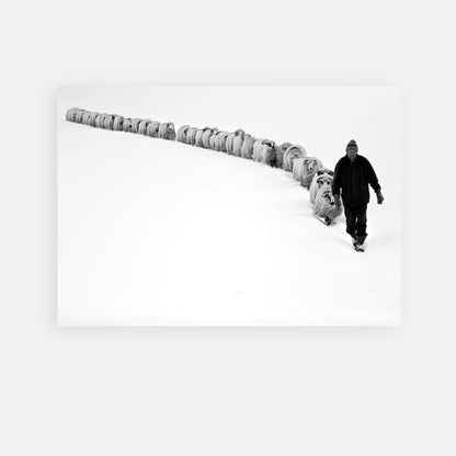 A shepherd walking through snow with a flock of sheep in a stunning black-and-white photography.
